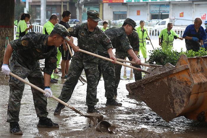 武警河北总队保定支队官兵在涿州市城西107国道沿线清理淤泥（8月5日摄）。